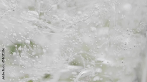 スーパースロー映像：夏の自然の中で、氷が入ったガラスのコップに炭酸水を注ぐ様子