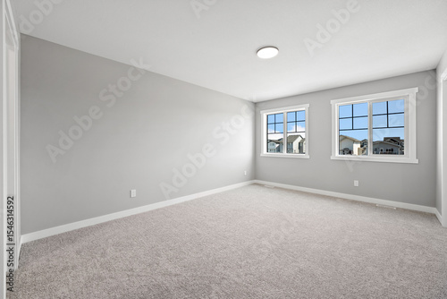 Large, empty room with a white wall and a tan carpet