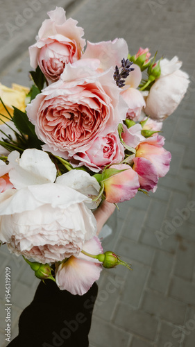 Vertical image of a delicate bouquet of spray roses in a hand