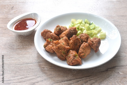 deep fried grouper fish patty on plate with slice cucumber dipping sweet chili sauce 