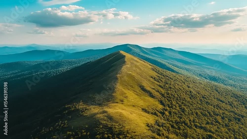 Aerial view of a lush green mountain ridge under a vibrant sky at sunset, showcasing nature's beauty