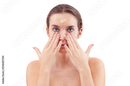 Young woman with natural skin applying foundation cream on face. Visible makeup strokes. Beauty closeup portrait, isolated on white background. Skincare and cosmetics routine, natural look concept.