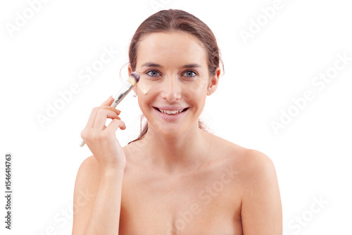 Smiling young woman with natural skin applying foundation with a makeup brush, visible streak on cheek. Skincare and beauty routine concept. Isolated on white background, clean and minimal look