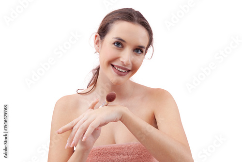 Smiling young woman tapping a makeup brush on the back of her hand before applying blush while looking into the camera. Clean, minimal beauty routine concept. Isolated on white background