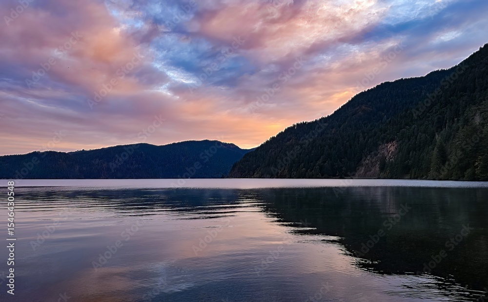 Fototapeta premium A serene lake reflecting the colorful sunset sky with mountains in the background