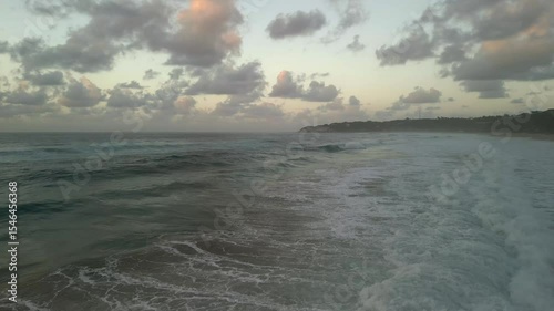 Ocean waves rolling towards tropical beach at sunset