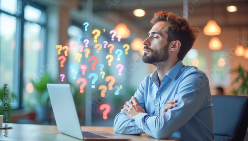 a man in an office is sitting with his eyes closed in front of a laptop with question marks around his head in space