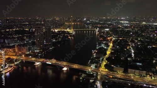 Aerial view of illuminated Rama VIII Bridge at night. Cable-stayed bridge crossing Chao Phraya River in Bangkok, Thailand, 4k