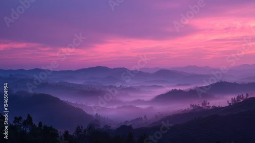 Foggy sunrise over hills with layered pink and purple sky