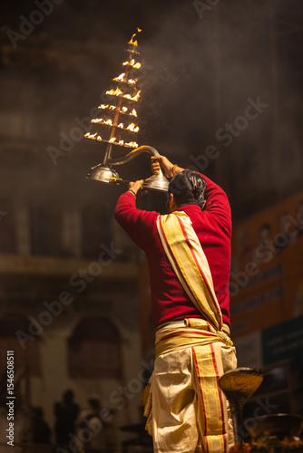 Ganga aarti, Portrait of an young unidentified male priest performing holy river ganga evening aarti at dashashwamedh ghat in traditional dress.