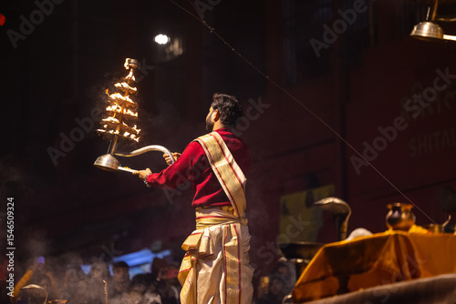 Ganga aarti, Portrait of an young unidentified male priest performing holy river ganga evening aarti at dashashwamedh ghat in traditional dress.