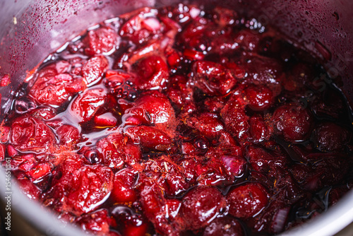 Cherry jam or sauce is cooked in a saucepan. Close-up. Background.