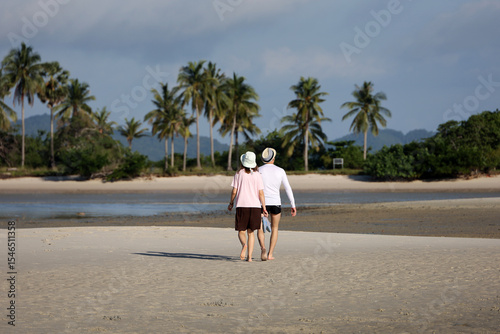 Couple walking on tropical beach on background of coconut palm trees
