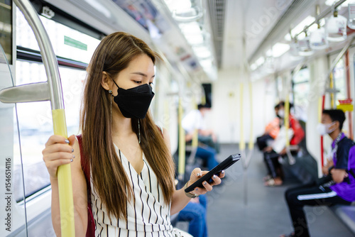 Asian woman is using a smartphone while waiting for the train at the station