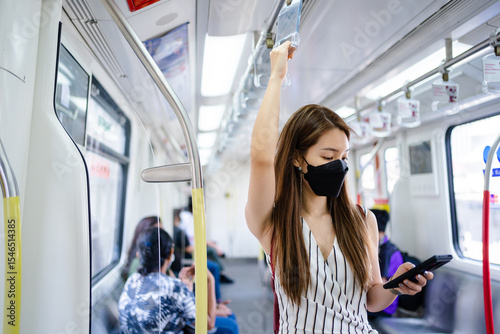 Asian woman is using a smartphone while waiting for the train at the station