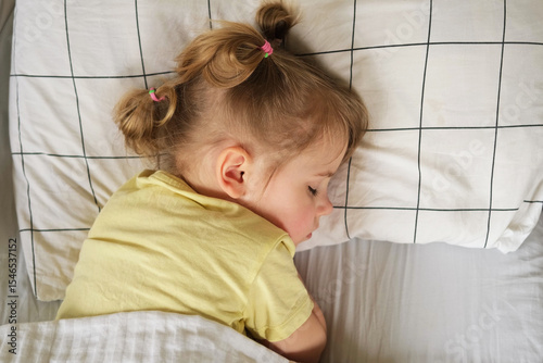 Peaceful adorable baby sleeping on a bed at home. Slumbering little child. Two years old girl sleeps peaceful at domestic room interior background. Serene dream. Cute face close up. Deep kid slumber