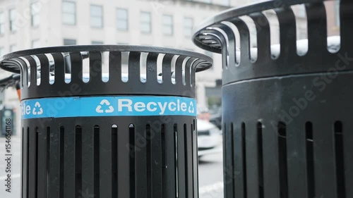 Recycle trash can on city street with cars going by
