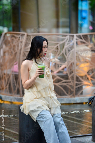 Elegant Woman Holding Matcha Green Tea with Wind Blown Hair Outdoors