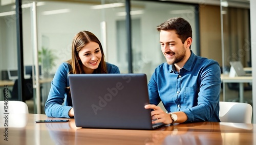 Smiling coworkers collaborating on laptop in modern office