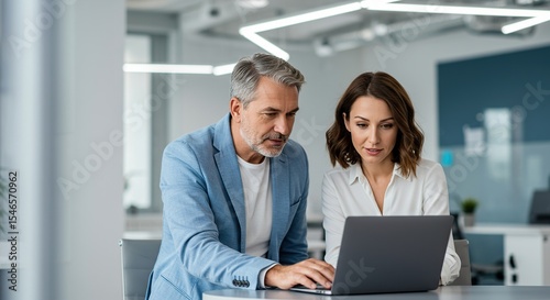 Business colleagues collaborating on laptop in modern office