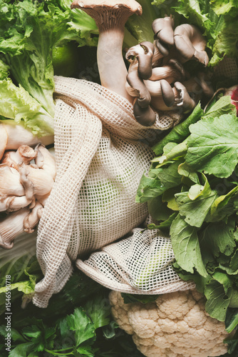 Fresh green vegetables and herbs in eco-friendly storage bag on vibrant backdrop for healthy meal preparation