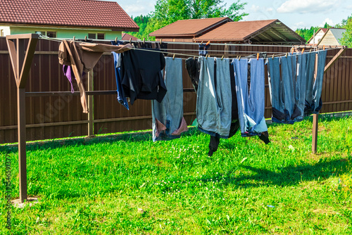Hanging jeans and clothing drying under the sun on a spring day in a backyard