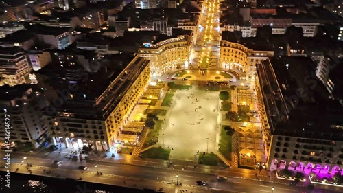 Aerial night view of Thessaloniki, Greece, captured by drone. Illuminated landmarks, city lights, and waterfront in cinematic 4K quality.