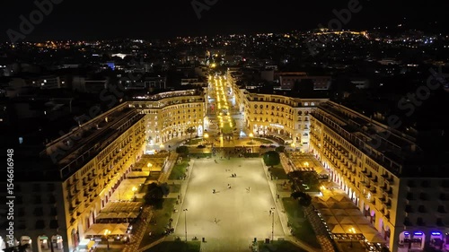 Aerial night view of Thessaloniki, Greece, captured by drone. Illuminated landmarks, city lights, and waterfront in cinematic 4K quality.