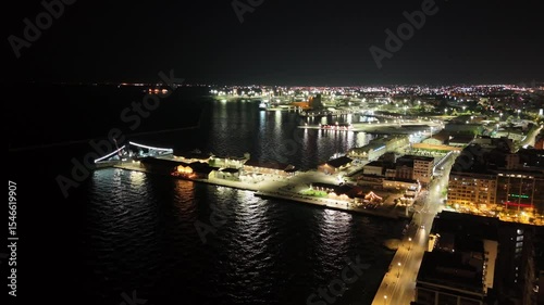 Aerial night view of Thessaloniki, Greece, captured by drone. Illuminated landmarks, city lights, and waterfront in cinematic 4K quality.