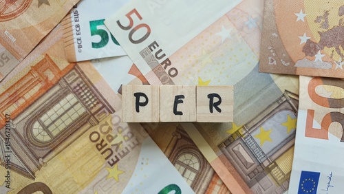 PER acronym made of wooden letter cubes on pile of Euro banknotes. Plan d’Épargne Retraite (Retirement Savings Plan)