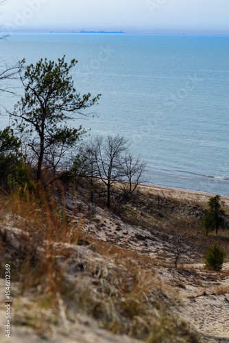 Sand dunes on the shore of a large lake, reflection of the sun in the water. Indiana Dunes National Lakeshore, USA.
