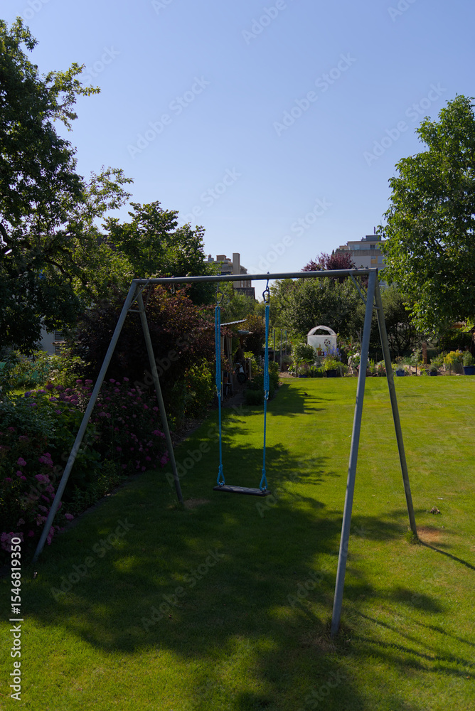 A classic swing set stands invitingly in a sun-drenched green backyard, evoking feelings of childhood joy, summer play, and carefree outdoor fun. Ideal for recreation and family themes. A classic swing set stands invitingly in a sun-drenched green backyard, evoking feelings of childhood joy, summer play, and carefree outdoor fun. Ideal for recreation and family themes.