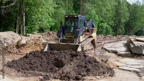 yellow wheel loader parked on forest trail renovation site