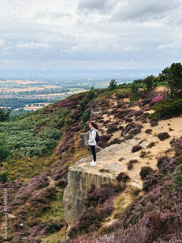 Woman standing at the edge of the mountain, heather season at North York Moors National Park, England, UK
