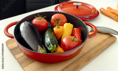 red beautiful cast iron skillet and fresh vegetables. cooking vegetable stew in cast iron. fresh vegetables and vegetarianism