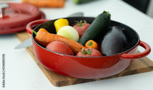 red beautiful cast iron skillet and fresh vegetables. cooking vegetable stew in cast iron. fresh vegetables and vegetarianism