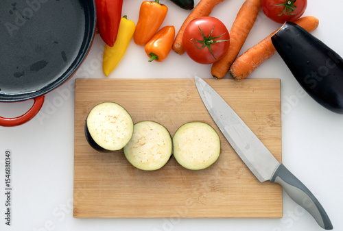 top view cutting board with knife and fresh vegetables: carrots, eggplant, tomatoes, onions, zucchini. cooking vegetable stew. benefits of fresh vegetable dishes, vegetarianism