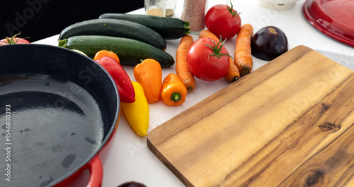red beautiful cast iron skillet and fresh vegetables. cooking vegetable stew in cast iron. fresh vegetables and vegetarianism
