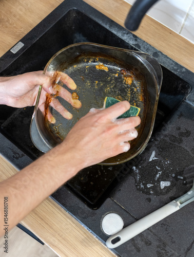close up girl washing glass baking dish by hand. washing greasy dirty dishes with yellow sponge and detergent