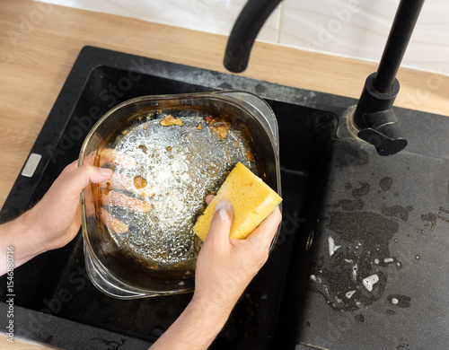 close up girl washing glass baking dish by hand. washing greasy dirty dishes with yellow sponge and detergent