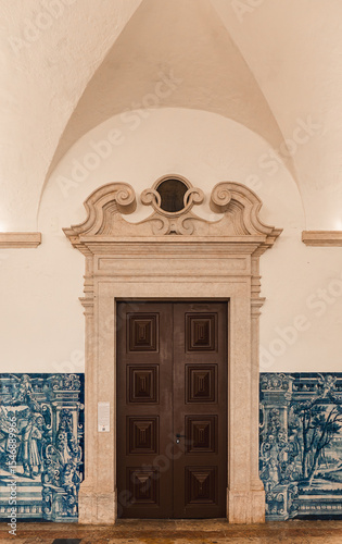 Classic Lisbon architecture featuring a grand wooden door framed by ornate stonework and traditional blue azulejo tiles, perfect for heritage, travel, and design inspiration.