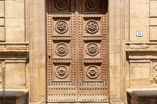 Large wooden front doors with circular patterns and steel bolts of the San Gaetano church