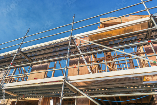 Scaffolding surrounds a building being constructed from wooden materials