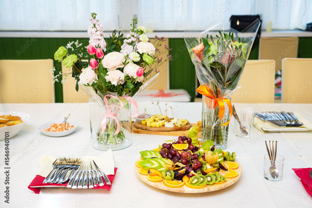 Fototapeta premium Festive table setting with fruit platter and flowers.