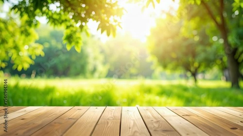 Sunlit meadow landscape backdrop with wooden platform for product placement, displaying a bright sunny day and green grass, trees.