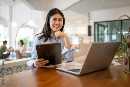 Free Download woman is sitting at a table with a laptop and tablet in front of her - GFXLoad