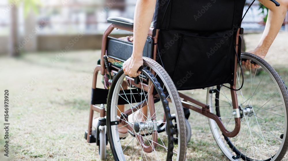 Obraz premium cropped shot, middle age female on wheelchair and hand grip on wheel on grass field at home she resting after being sick