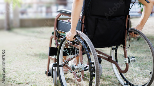 cropped shot, middle age female on wheelchair and hand grip on wheel on grass field at home she resting after being sick