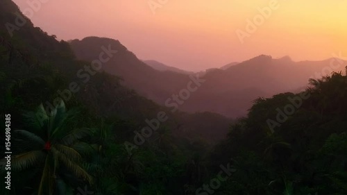 Serene Sunset Hues Over Misty Tropical Valley and Palm Trees