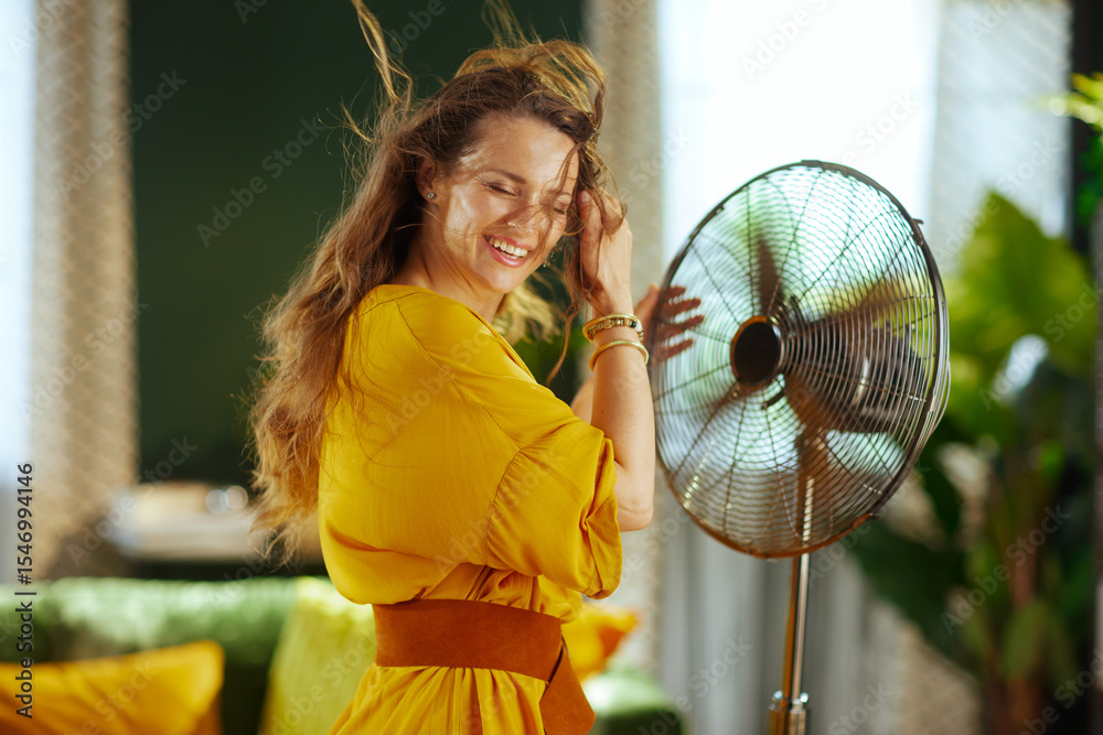 Naklejka premium Woman Joyfully Embracing Fan\'s Cool Air